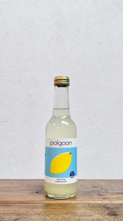 A bottle of Polgoon sparkling Lemonade on a table. Cloudy Sicilian lemonade made in Penzance, Cornwall at Polgoon Vineyard